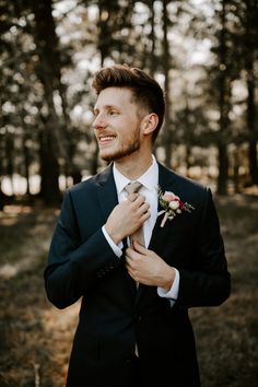 a man in a suit and tie standing in the woods