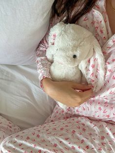 a woman in bed holding a white stuffed animal