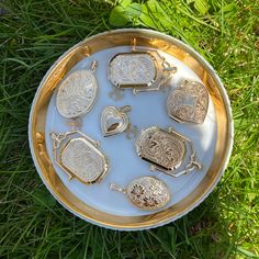 there are many silver items in the bowl on the grass and one is missing it's lid