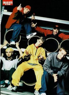 a group of young men sitting next to each other in front of metal pipes with their hands up