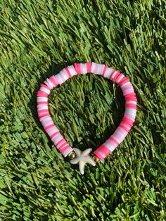 A multicolored pink bracelet with a starfish charm. Pink Beaded Bracelets For Vacation, Pink Beaded Bracelets For Summer Gifts, Vacation Pink Friendship Bracelets With Colorful Beads, Pink Beaded Bracelet For Vacation, Pink Beaded Friendship Bracelets For Vacation, Beachy Pink Bracelets As Gift, Handmade Pink Friendship Bracelets For Vacation, Pink Beaded Bracelets For Beach, Pink Beachy Bracelets For Beach Season