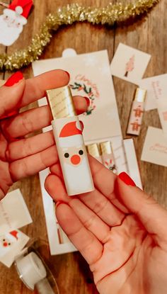 a person holding an electronic device in their hand with christmas decorations on the table behind them