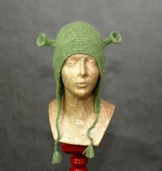 a mannequin head wearing a green knitted hat on top of a wooden base