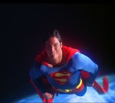 a man in a superman costume is floating on the water with his arms out and legs spread wide