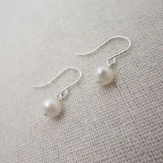 Dainty and classic, these sterling silver earrings are made with real pearls in a creamy off-white color. The TINY pearls are approximately 5mm. Each pair comes in a gift box, perfect for gift giving.  Comes with hypo-allergenic and comfortable rubber earring stops to keep hooks securely in your ear.  Shown on a life-sized mannequin for size-reference. Total earring length is approximately 3/4 inch.  Please note, these are made with genuine freshwater pearls so sizes, shapes, and coloring will v Classic Pearl Drop Earrings, Classic Silver Pearl Earrings For Everyday, Everyday Pearl White Pearl Earrings, Everyday White Pearl Pendant Earrings, Classic Everyday Pearl Drop Earrings, Classic Everyday Nickel Free Pearl Earrings, Classic Nickel-free Pearl Earrings, Everyday Hypoallergenic Pearl White Pearl Earrings, Classic Sterling Silver Pearl Drop Earrings