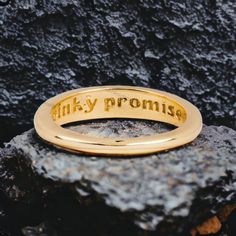 a gold ring with the words inky prom written on it sitting on top of a rock