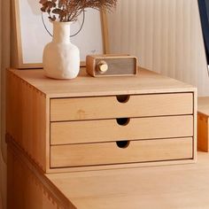 a white vase sitting on top of a wooden dresser