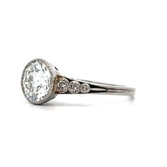 a white gold ring with an oval cut diamond and three small diamonds on the band