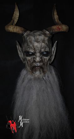 an evil looking mask with horns and long hair