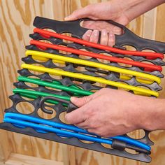 two hands are holding an assortment of multicolored handles on a wooden wall with wood paneling