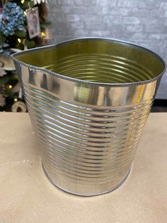 a large metal bucket sitting on top of a table next to a christmas tree in the background