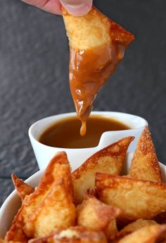 a person dipping sauce on some food in a bowl