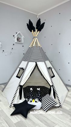 a teepee tent with black and white decorations on the floor in a child's room