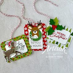 three christmas tags hanging on a white surface with red and green ribbons around them,