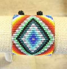 "Colorful and vibrant -- a meticulously designed creation that features a beautiful design and colorful pattern. The bracelet can also act as an anklet.  A ball of beads at the ends works as a clasp for a secure fit. Measurements: Length (including clasp): 7.5\" inches Width: 2\" inches" Hand-strung Multicolor Beaded Bangle, Multicolor Hand-strung Beaded Bangle, Adjustable Multicolor Bead Bangles, Adjustable Multicolor Beaded Bracelet For Festival, Multicolor Hand-strung Friendship Bracelets, Traditional Multicolor Beaded Bracelets For Festival, Spiritual Multicolor Beaded Bangle Bracelets, Hand-strung Multicolor Friendship Bracelets For Festivals, Multicolor Round Beads Friendship Bracelets For Festivals