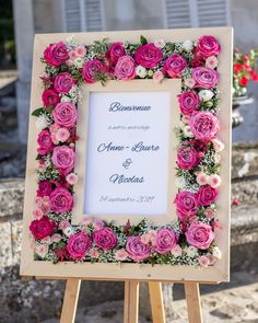 a wooden easer holding a pink and white flowered wedding sign on it's side