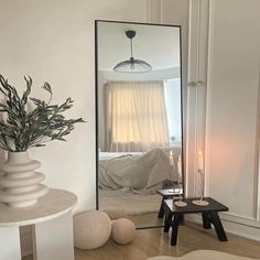 a mirror sitting on the side of a wall next to a table with a vase