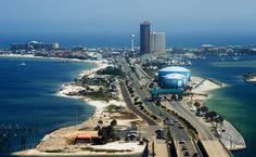 an aerial view of a city and the ocean with cars driving down it's road