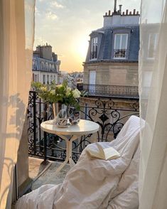 a balcony with a table and chairs on it, overlooking the cityscape at sunset