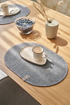 a wooden table topped with plates and cups