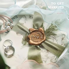 wedding rings and ring box with the words to get married on it, surrounded by other accessories