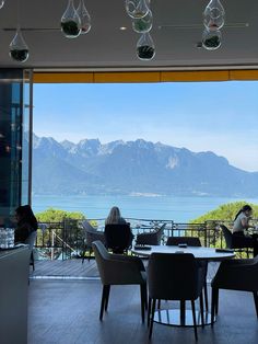 a woman sitting at a table in front of a window looking out on the mountains