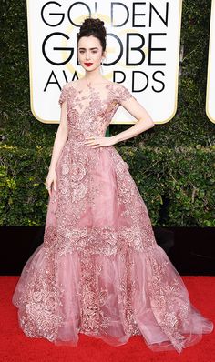 a woman in a pink gown on the red carpet at an awards event with her hands on her hips