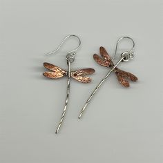 "Dragonfly earrings done in sterling silver & flame patinaed copper. Wings measure approx. 1\" wide and length including earwire is approx. 2 1/4 inch (give or take a bit on the length). Sterling earwires & dragonfly body, copper wings. Flame patina on the copper will vary! These have turned out to be one of my most popular earring creations! due to the hand made nature of these, each earring itself is individually made by hand, there may be slight variances between the photographs and the earri Unique Rust-colored Earrings With Ear Wire, Unique Rust Earrings With Ear Wire, Artistic Silver-colored Copper Earrings, Artistic Silver Copper Earrings, Unique Silver-colored Copper Earrings, Rust Hand Forged Earrings As Gift, Hand Forged Rust Earrings As Gift, Hand Forged Brown Earrings As A Gift, Hand Forged Silver Copper Earrings