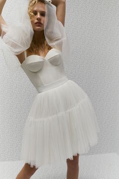 a woman in a white dress and veil posing for the camera with her hands on her head