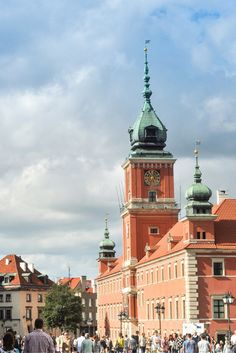 people are walking around in front of an old building with a clock tower on top