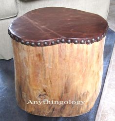 a round wooden table sitting on top of a black leather floor next to a white couch