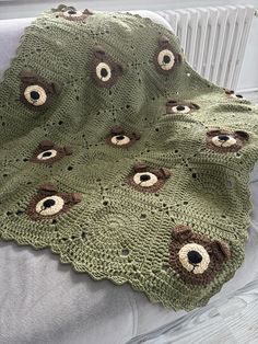 a crocheted blanket with eyeballs on it is sitting on a chair next to a radiator