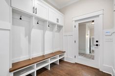 a large white mud room with wooden benches