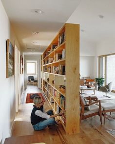 a woman sitting on the floor in front of a bookshelf filled with books