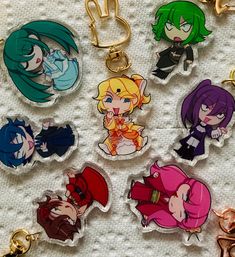 some anime key chains are laying out on a white tablecloth with various colors and designs