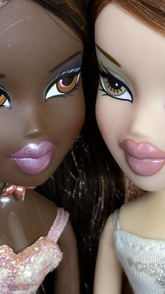 two dolls are posed next to each other, one is brown and the other is pink