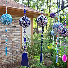 an assortment of colorful glass ornaments hanging from a tree in front of a brick building