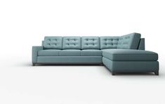 a blue sectional couch sitting on top of a white floor next to a footstool