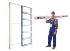 a man in overalls is holding a large piece of wood and standing next to a metal rack