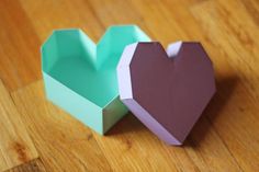 two heart shaped boxes sitting on top of a wooden table