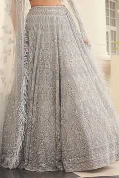 Grey attached cancan lehenga with sequin, cutdana, bead, thread embroidery in geometric pattern. Paired with half sleeve embroidered padded blouse and feather border embellished net dupatta.
Components: 3
Pattern: Embroidery
Type Of Work: Sequin, cutdana, bead, thread
Neckline: Leaf neck
Sleeve Type: Half sleeves
Fabric: Net
Color: Grey
Other Details: 
Lehenga:
Attached cancan
Geometric pattern
Length: Approx 43 - 44 inches
Blouse:
Padded
Crystal drops on blouse hem
Dupatta:
Feather embellished Semi-stitched Net Sharara Floor-length, Traditional Net Dresses With Mirror Work, Semi-stitched Net Gown For Eid, Designer Net Dresses For Diwali, Net Dresses For Designer Wear During Diwali, Anarkali Net Gown For Diwali, Diwali Dresses With Intricate Embroidery, Wedding Net Sets For Eid, Festive Floor-length Net Anarkali Set