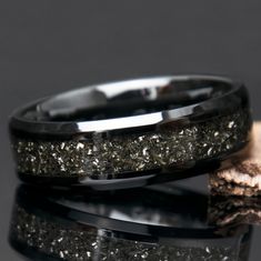 two wedding bands with gold and silver glitters on them, one is black and the other is white