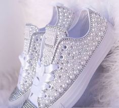 a pair of white sneakers with pearls and bows on the side, all covered in silver sequins