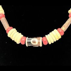 This necklace is handcrafted and looks stunning on any skin tone. It features a combination of yellow and red beads, accentuated with tribal-style glass beads, all brought together in the center. The vibrant colors of this necklace will definitely make heads turn and add a touch of class, flavor, and warmth to any outfit. It's a unique and eye-catching choker that will transform your look and leave a lasting impression. The necklace is 17 inches long and has a secure magnetic closure. Traditional Wooden Beads Jewelry For Beach, Bohemian Orange Hand-strung Necklace, Hand-strung Bohemian Glass Beaded Necklaces, Bohemian Hand-strung Glass Beaded Necklaces, Hand-strung Glass Bohemian Beaded Necklaces, Traditional Orange Necklace For The Beach, Unique Glass Necklaces For The Beach, Bohemian Orange Oval Beads Necklace, Bohemian Orange Oval Beaded Necklaces