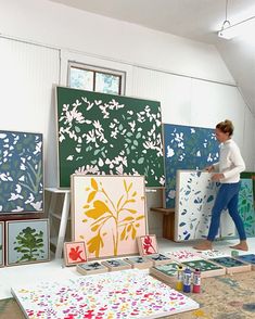 a woman standing in front of paintings on easels