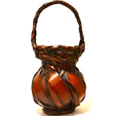 an orange vase with braided handles on a white background in the shape of a basket