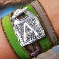 a close up of a person's arm wearing bracelets with an initial on it