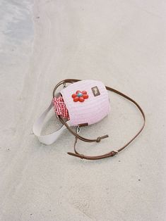 a pink purse sitting on top of a beach next to the ocean with a strap around it