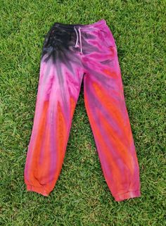 a pair of pink and black tie - dyed sweatpants laying on the green grass