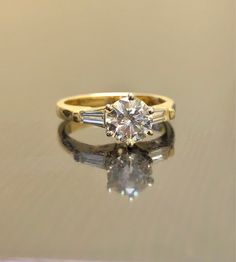 a yellow gold ring with two baguettes on the side and a diamond in the middle